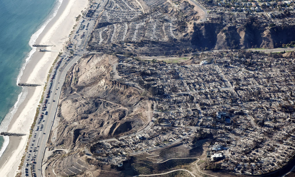 An aerial view of fire trucks, utility, and other vehicles parked along Pacific Coast Highway near homes destroyed in the Palisades Fire as wildfires cause damage and loss through the LA region on January 13, 2025 in Pacific Palisades, California. Photo by Mario Tama/Getty Images