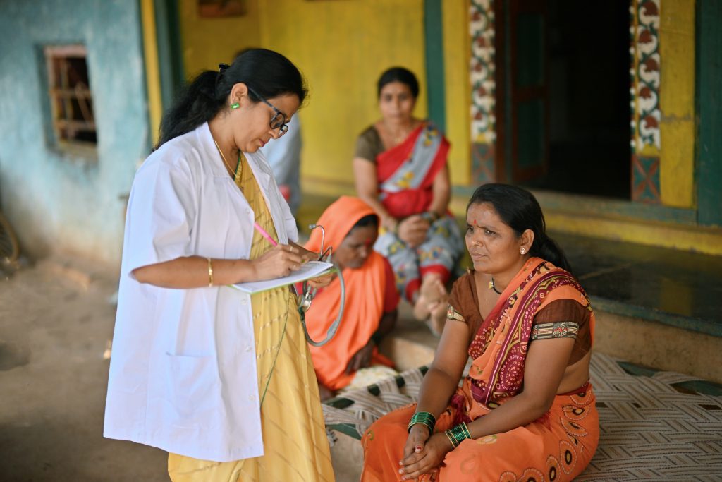 Doctor giving out prescription to a rural woman during  a rural health care camp