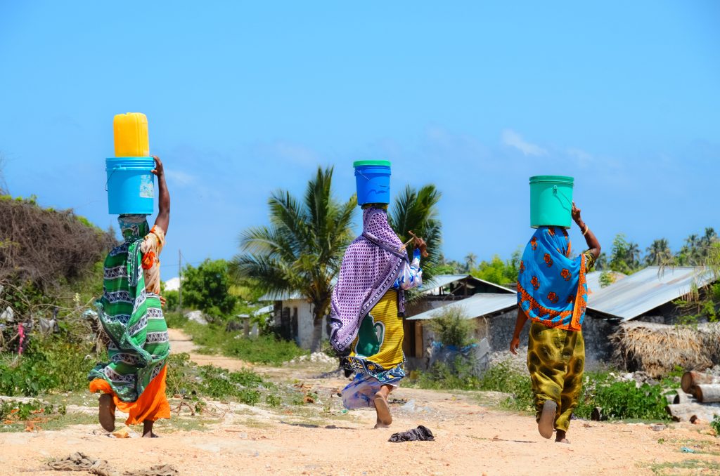 African women go to fetch water w/ buckets on head