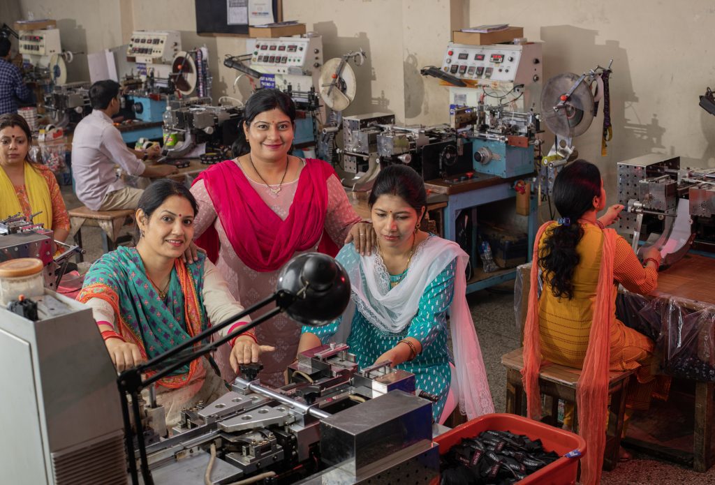 Confident female coworkers operating machineries at textile factory