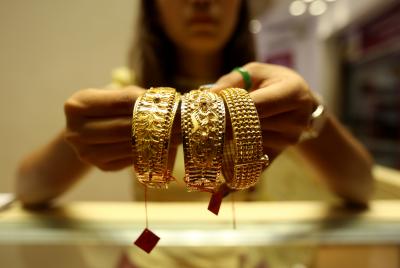 Gold edges lower on stronger dollar, Fed minutes weigh on rate-cut hopes